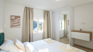 A hotel room with two beds, a bathroom, a view of the sea, and a mirror. - Nice home in Karbuni with WiFi (Karbuni)