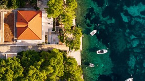 A coastal property with a red-roofed building, clear turquoise waters, and several boats. - Nice home in Karbuni with WiFi (Karbuni)