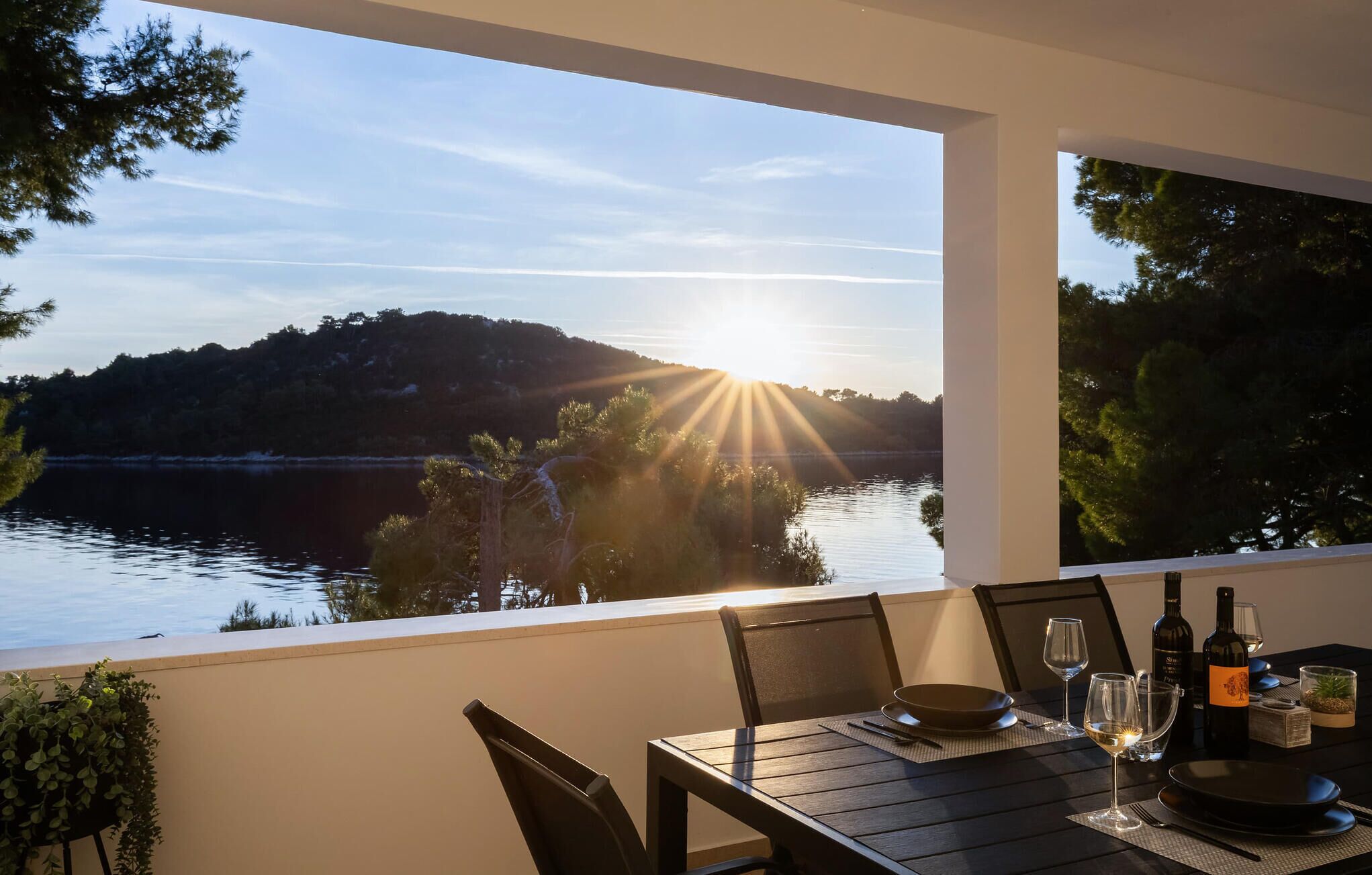 Ein Essbereich mit einem Tisch für zwei Personen mit Blick auf einen See und einem Sonnenuntergang.