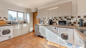 A modern kitchen with a washing machine, dishwasher, microwave, and a coffee maker. - 3 Bed in East Allington (oc-m30710) (East Allington)