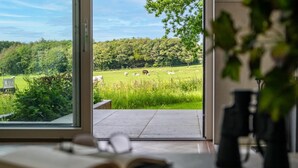 Een kamer met een groot raam dat uitkijkt op een grasveld met dieren.