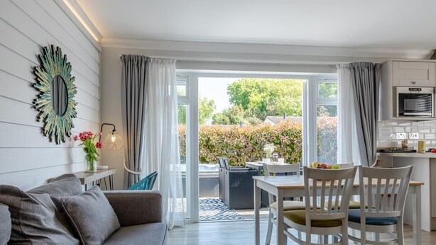 Un salon moderne avec un canapé gris, une table à manger avec des chaises et un coin cuisine équipé d’un four à micro-ondes.
