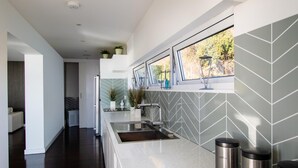 Una cocina moderna con un ventanal grande, salpicadero de baldosas en espiga y electrodomésticos de acero inoxidable.