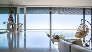 Una sala de estar moderna con un ventanal grande con vista al mar, un sillón colgante y un diseño minimalista.