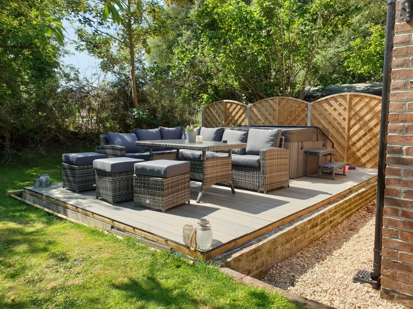 An outdoor patio with wicker furniture, a table, and a brick wall.