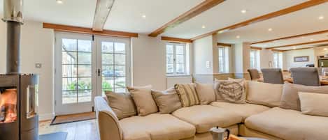 A modern living room with a sectional sofa, a fireplace, and a dining area with chairs.