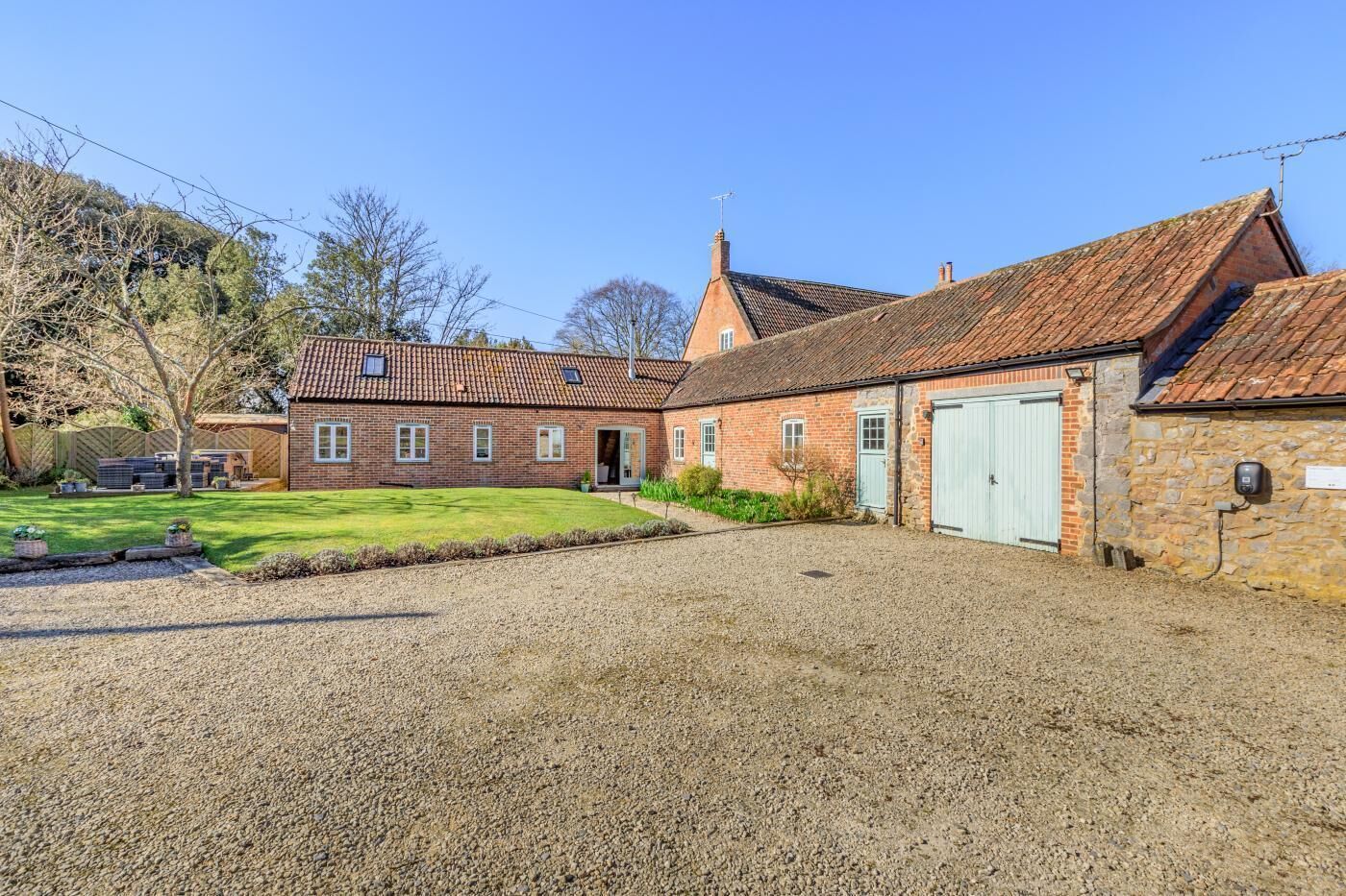 A brick building with a gravel driveway and a green lawn.
