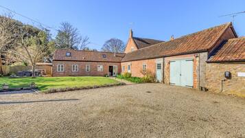 A brick building with a gravel driveway and a green lawn.
