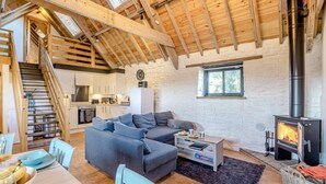 A cozy living room with a sofa, a dining table with chairs, a kitchen area, and a fireplace. - 2 Bed in Clevedon (oc-t30786) (Clavedon)