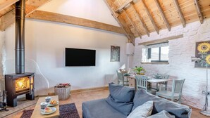A cozy living room with a fireplace, a TV mounted on the wall, and a dining area with a table and chairs. - 2 Bed in Clevedon (oc-t30786) (Clavedon)
