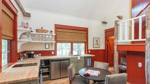 Une cuisine avec un plan de travail en bois, une table à manger avec des chaises et une fenêtre avec un store.