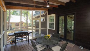 Une terrasse extérieure avec une table ronde, des chaises, un barbecue et un ventilateur de plafond.