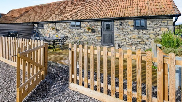 A stone building with a tiled roof, a wooden fence, and a gravel driveway. - 2 Bed in Clevedon (oc-s30785) (Clavedon)