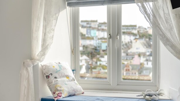A room with a window seat, a plush toy, and a patterned pillow. - 2 Bed in Brixham (oc-w30730) (Brixham)