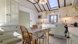 Una cocina con una mesa de comedor, sillas y un ventanal sobre el fregadero.