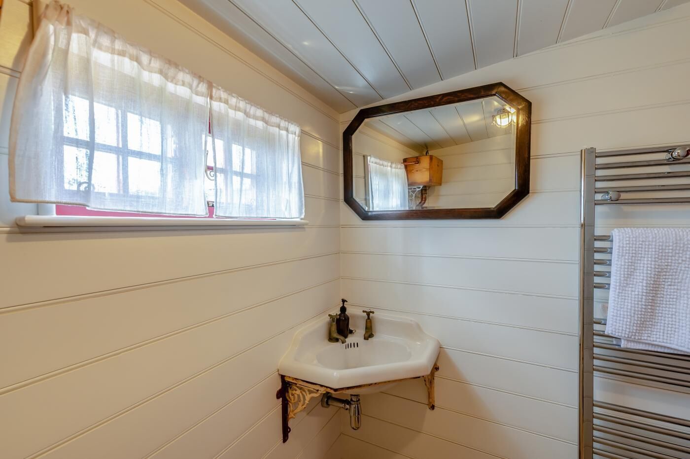 Une salle de bain avec un lavabo blanc, un miroir et un porte-serviettes.