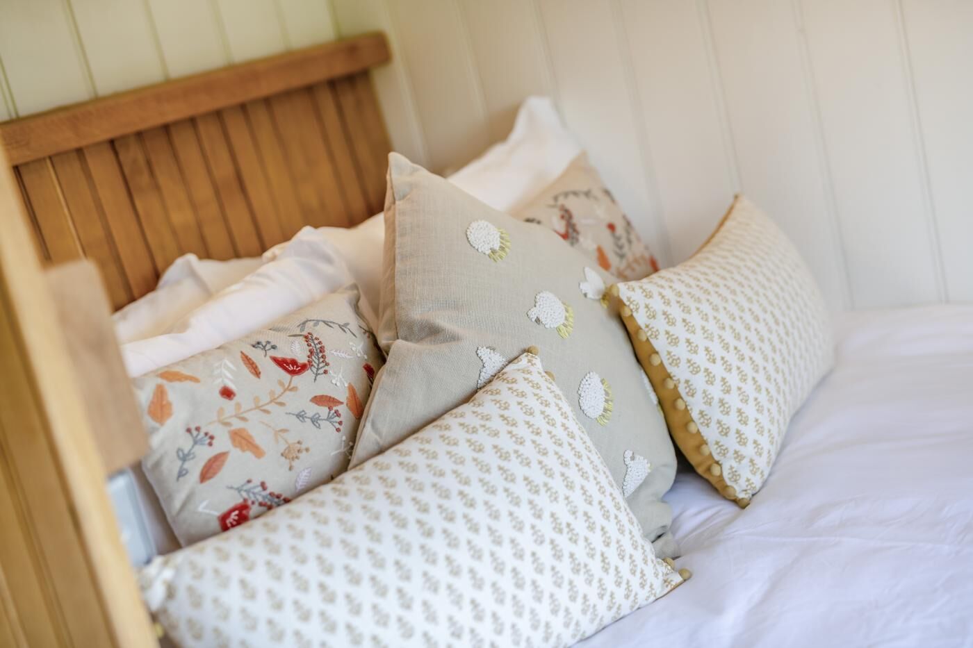 Una cama con cabecera de madera y varios almohadones con diferentes diseños.