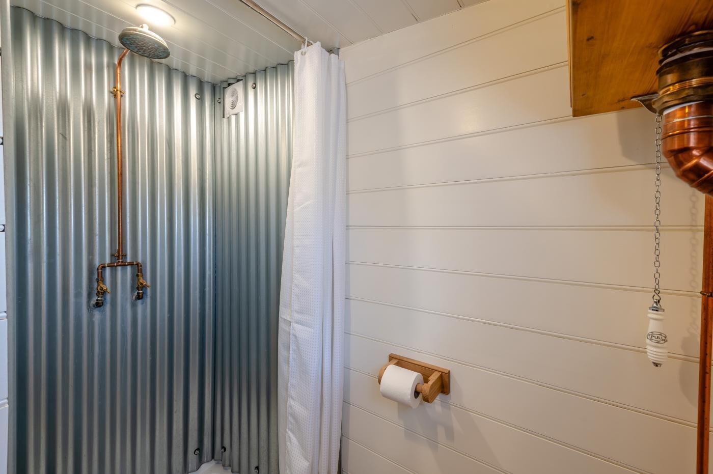 Un bagno con doccia, un water e un portasciugamani.