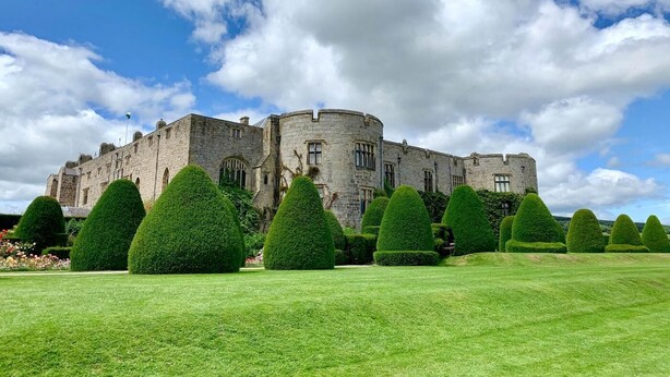 Un ch âteau historique en pierre, doté d’une pelouse parfaitement entretenue et de buissons taillés avec soin.