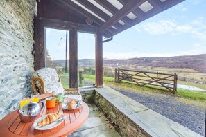 A breakfast setup with a table, chairs, and a scenic view of a valley. - 1 Bed in Llandderfel (oc-t30475) (Llandderfel)