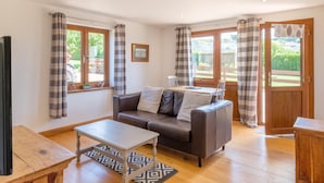Ein gemütliches Wohnzimmer mit einem braunen Ledersofa, einem Holztisch und Karosospendern.