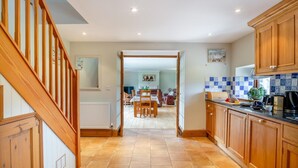 Una cocina con armarios de madera, piso de baldosas y un comedor con mesa y sillas.