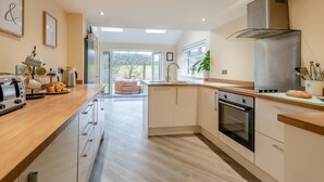Una cucina moderna con un piano di lavoro in legno, elettrodomestici in acciaio inossidabile e vista sull'esterno.