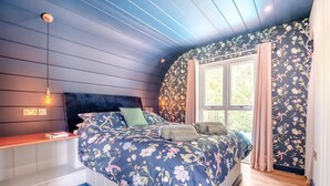 A bedroom with a bed, a bench, a window, and a floral wallpaper. - 1 Bed in Newport (oc-f30846) (Newport)