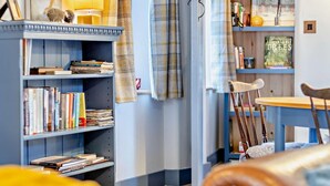 A cozy reading nook with a bookshelf, a small table, and a chair. - 2 Bed in Pentre Bach (oc-b30875) (Pentre-bach)