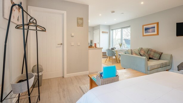 A modern living room with a sofa, a dining area, and a kitchen in the background. - 1 Bed in Coldingham (oc-c30814) (Coldingham)