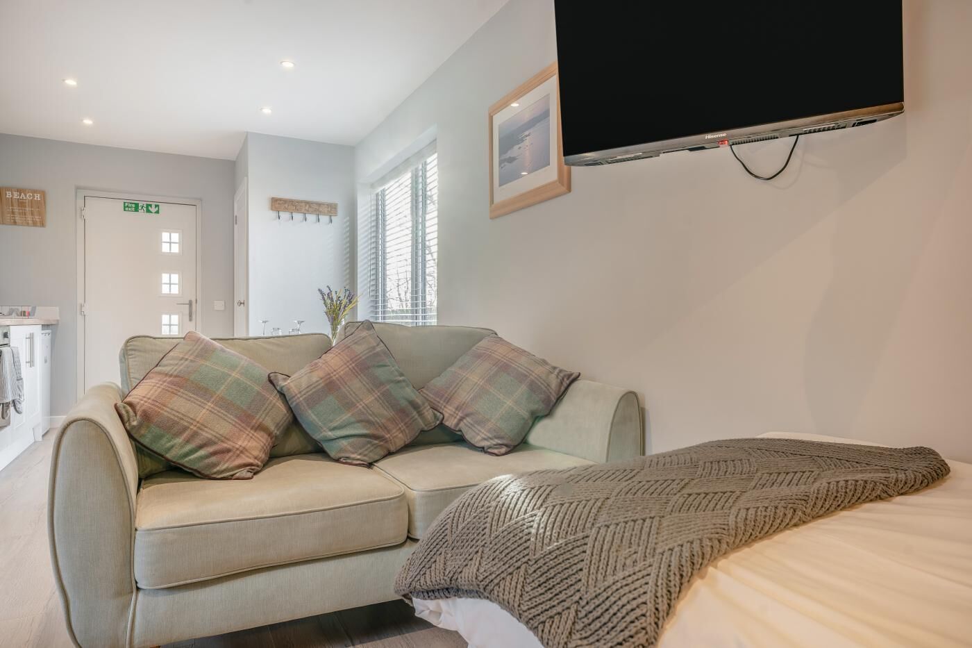 Ein gemütliches Zimmer mit einer Couch, einem Bett, einem Flachbildfernseher und einem Fenster mit Jalousien.