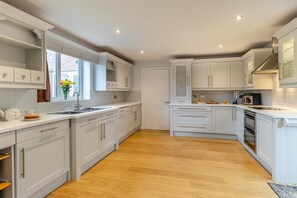 Una cocina moderna con armarios blancos, piso de madera y horno empotrado.