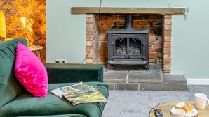A cozy living room with a green sofa, a fireplace, a magazine, and a table with a croissant and coffee cups. - 4 Bed in Brecon (oc-h30823) (Brecon)