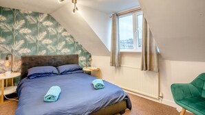 A bedroom with a bed, a nightstand, a lamp, a window, and a green chair. - 4 Bed in Brecon (oc-h30823) (Brecon)
