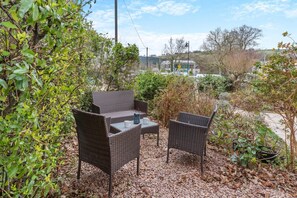 An outdoor seating area with wicker furniture, a table, and a pitcher. - 4 Bed in Brecon (oc-h30823) (Brecon)