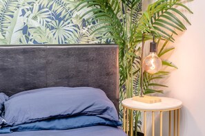A bed with dark blue bedding, a grey headboard, and a round side table with a lamp. - 4 Bed in Brecon (oc-h30823) (Brecon)
