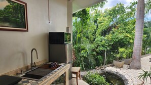 Un baño con lavamanos, espejo y un refrigerador pequeño.