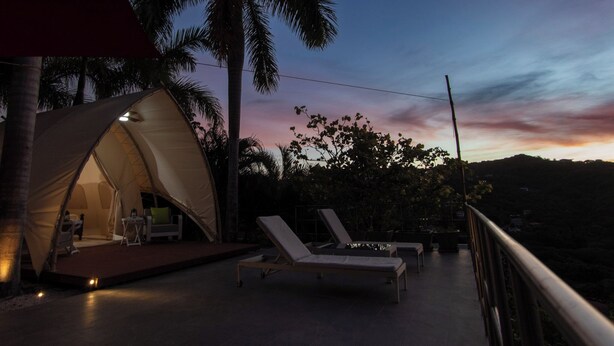 Eine Zeltoase mit Lounge-Sesseln und einem malerischen Sonnenuntergang.
