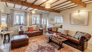 A spacious living room with a large brown leather sofa, a smaller sofa, a coffee table, and a patterned rug. - 4 Bed in East Morton (oc-t30809) (East Morton)
