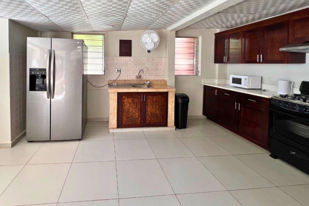 A kitchen with a stainless steel refrigerator, a microwave, a stove, and wooden cabinets.