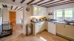 Una cocina moderna con armarios blancos, un lavavajillas de acero inoxidable y un ventanal que proporciona luz natural.
