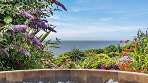 A garden with a variety of colorful flowers and a wooden planter filled with ice. - 1 Bed in Millbrook (oc-b30672) (Tregonhawke)