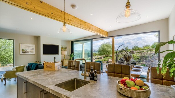 Una cucina moderna con una grande isola, un'area pranzo con vista e un angolo salotto accogliente.