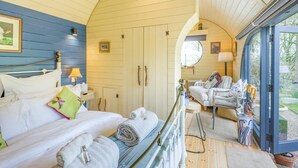 Ein Schlafzimmer mit Bett, Stuhl, kleinem Tisch und Fenster.