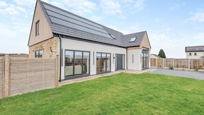 Ein modernes Haus mit großem Glasflügelfront, Steinaußenwand und geneigtem Dach.