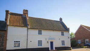 A two-story white building with a dark roof, a blue door, and a small porch. - 2 Bed in Horsham St. Faith (oc-b30838) (Horsham Saint Faith)