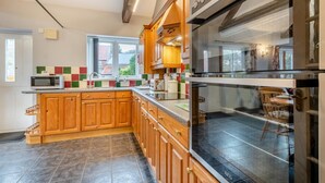 A modern kitchen with wooden cabinets, a large oven, and a window overlooking a residential area. - 2 Bed in Horsham St. Faith (oc-b30838) (Horsham Saint Faith)
