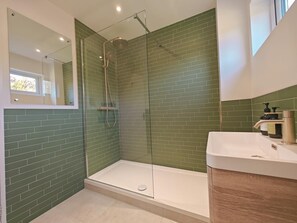 A modern bathroom with a glass-enclosed shower, green-tiled walls, and a white sink with toiletries. - 5 Bed in Tealby (oc-t30618) (Tealby)