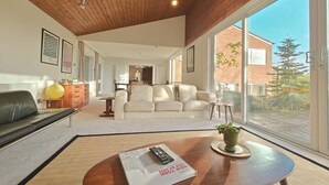 Uma sala de estar moderna com sofá, mesa de centro e uma grande janela com vista para o exterior.