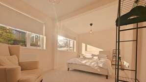 Um quarto com uma cama, uma cadeira e uma cama beliche.